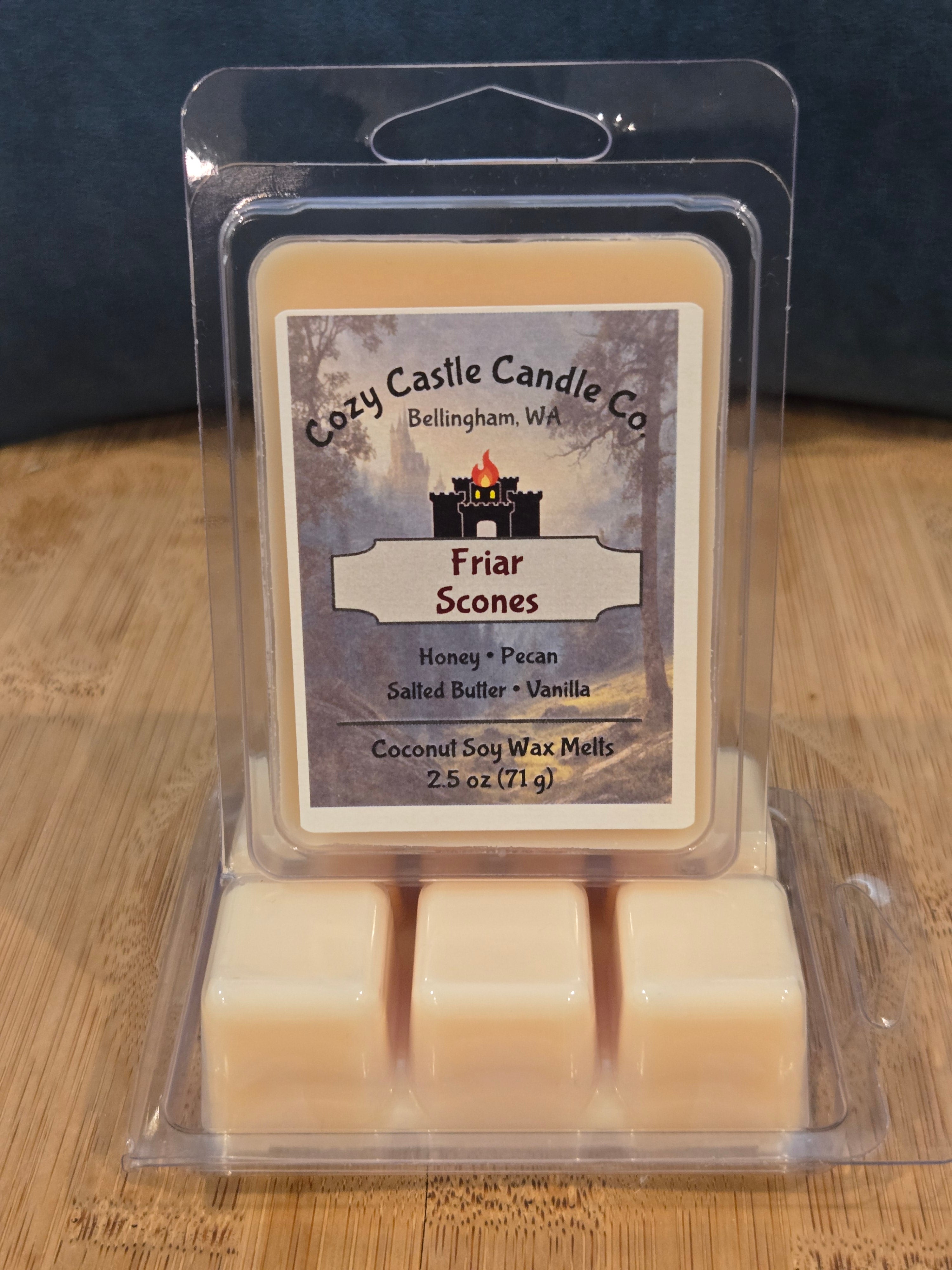 Cozy Castle Candle Co. wax melts in packaging on a wooden surface. Friar Scones, with notes of Honey, Pecan, Salted Butter, and Vanilla.