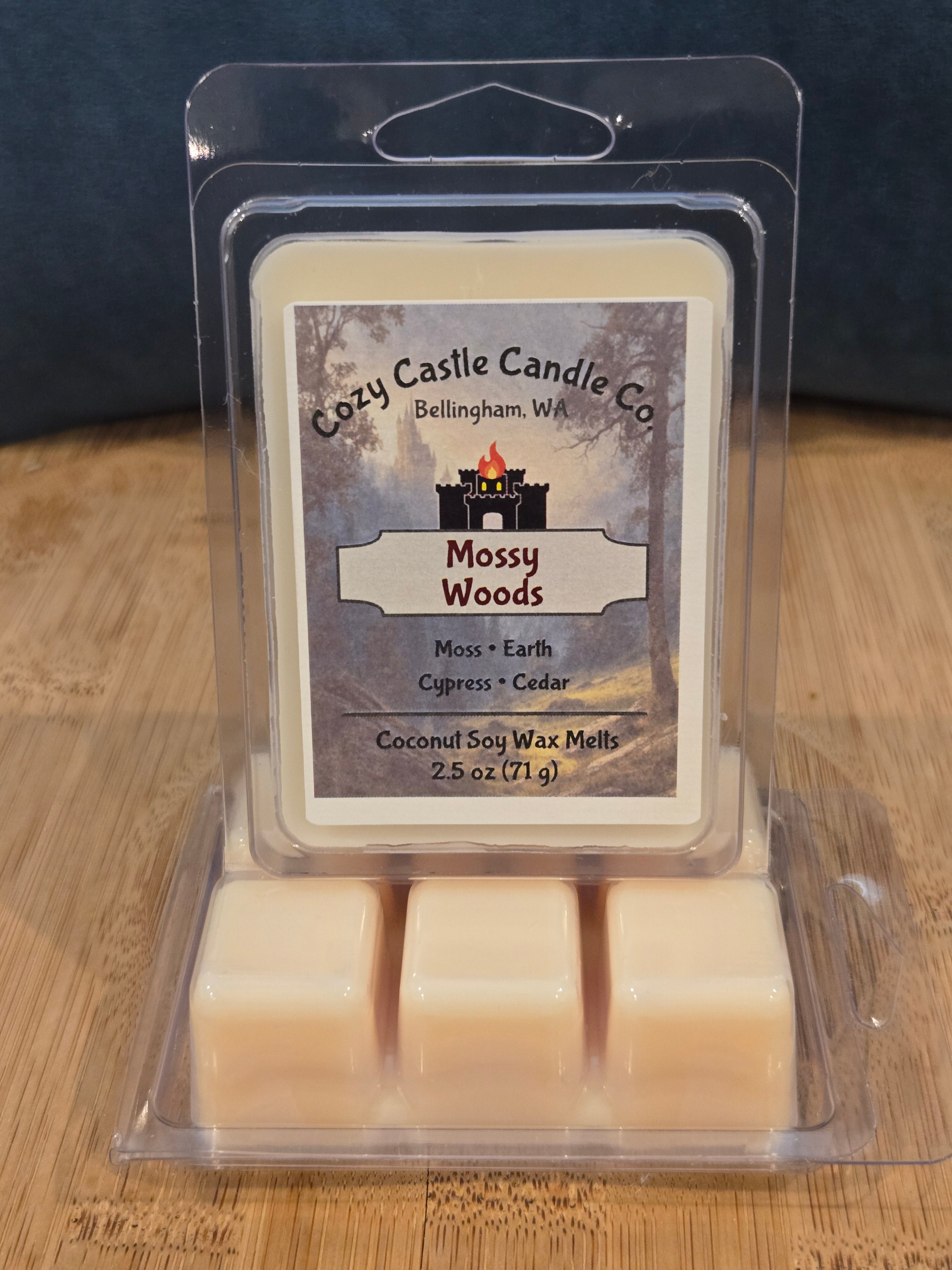 Cathy Castle Candle Co. Mossy Woods wax melts in packaging on a wooden surface. Mossy Woods, with notes of Moss, Earth, Cypress and Cedar.