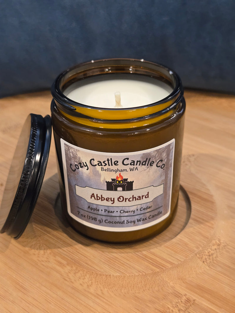 Jar Candle on a wooden surface. Abbey Orchard, with notes of Apple, Pear, Cherry, and Cedar.