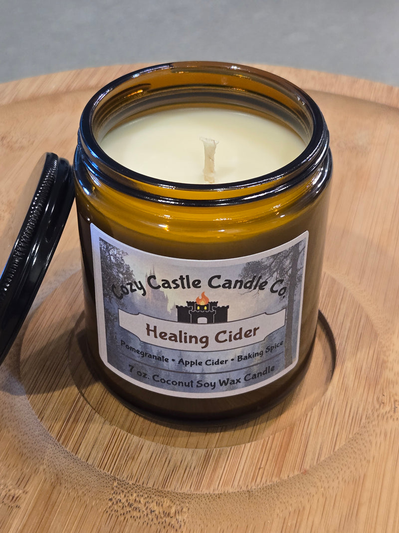 Candle labeled "Healing Cider" on a textured wooden surface.