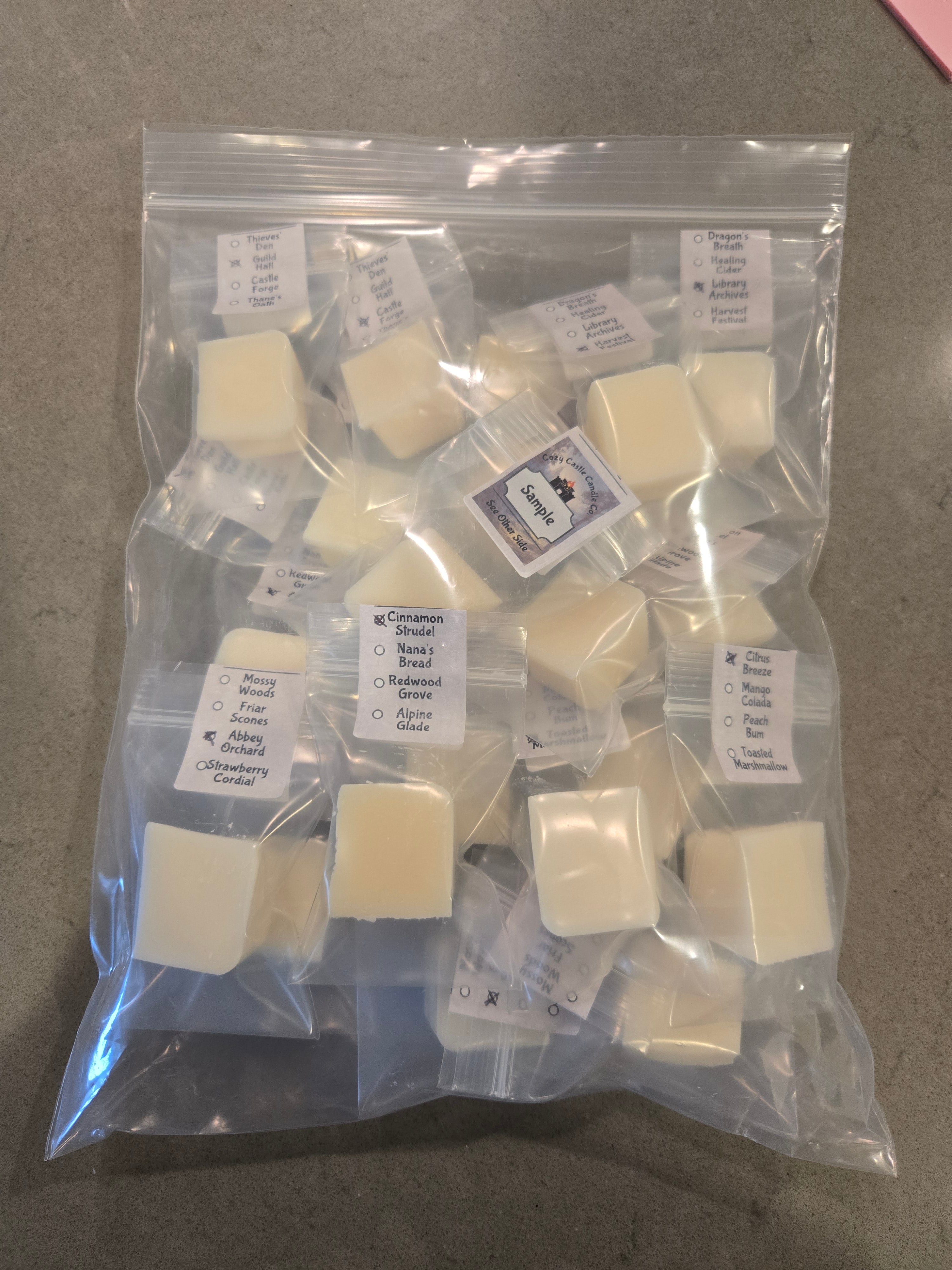 Individually Packaged wax melt cubes with labels on a gray surface